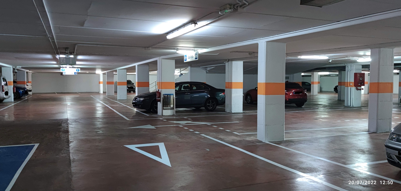 Interior de aparcamiento en Lugo con señalización de salida y autos estacionados.